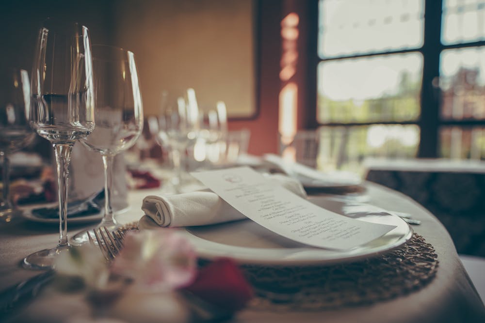 Elegant table setting with wine glasses, a rolled napkin, and a printed menu on a plate